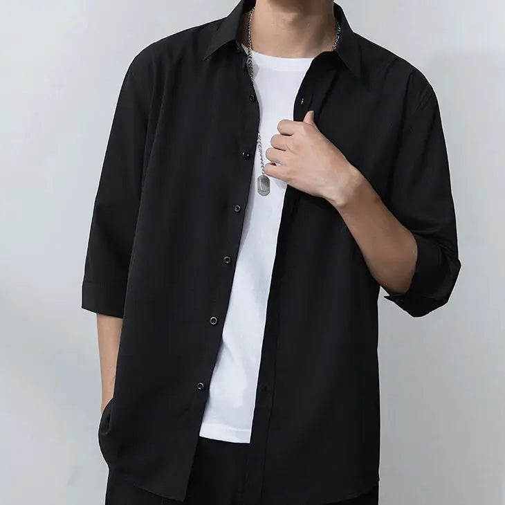 Julian's |Person wearing a black shirt over a white shirt with a gray background