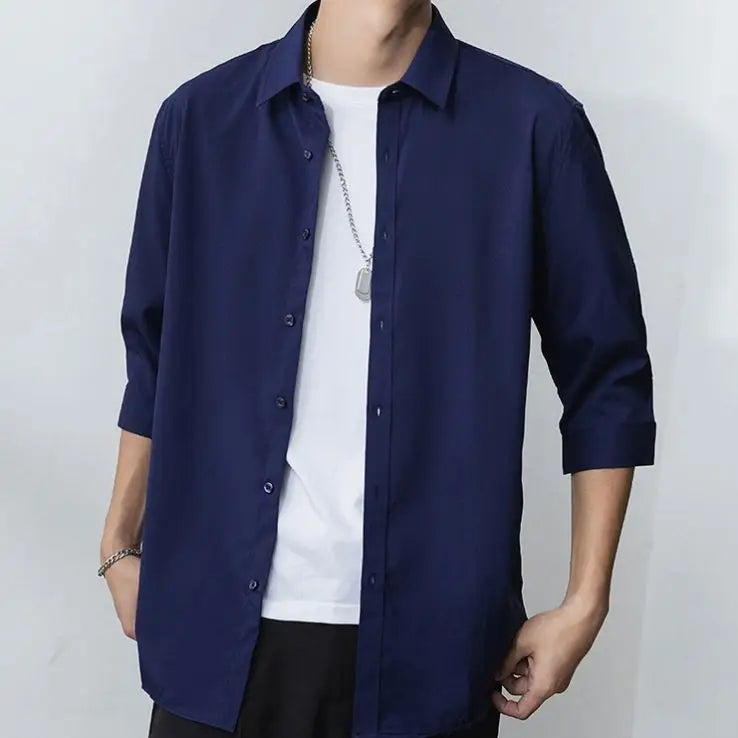 Julian's |Person wearing a navy blue shirt over a white t-shirt on a plain background