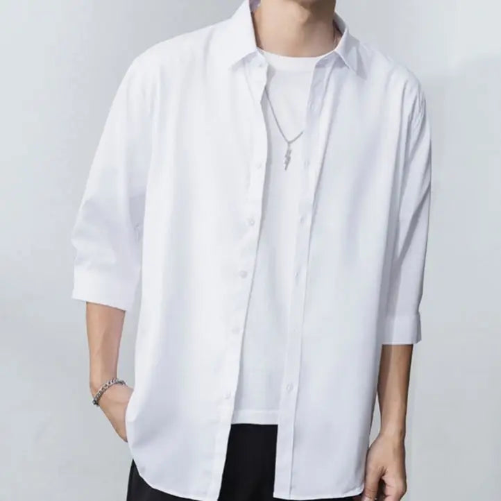 Julian's |Person wearing a white shirt with rolled-up sleeves on a plain background